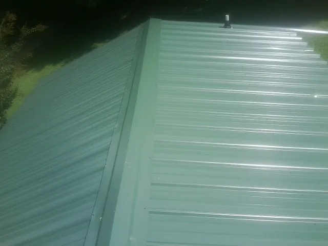 New green metal panels meeting at the ridge of a roof — Flat Roof Repair work by our crew in Croydon